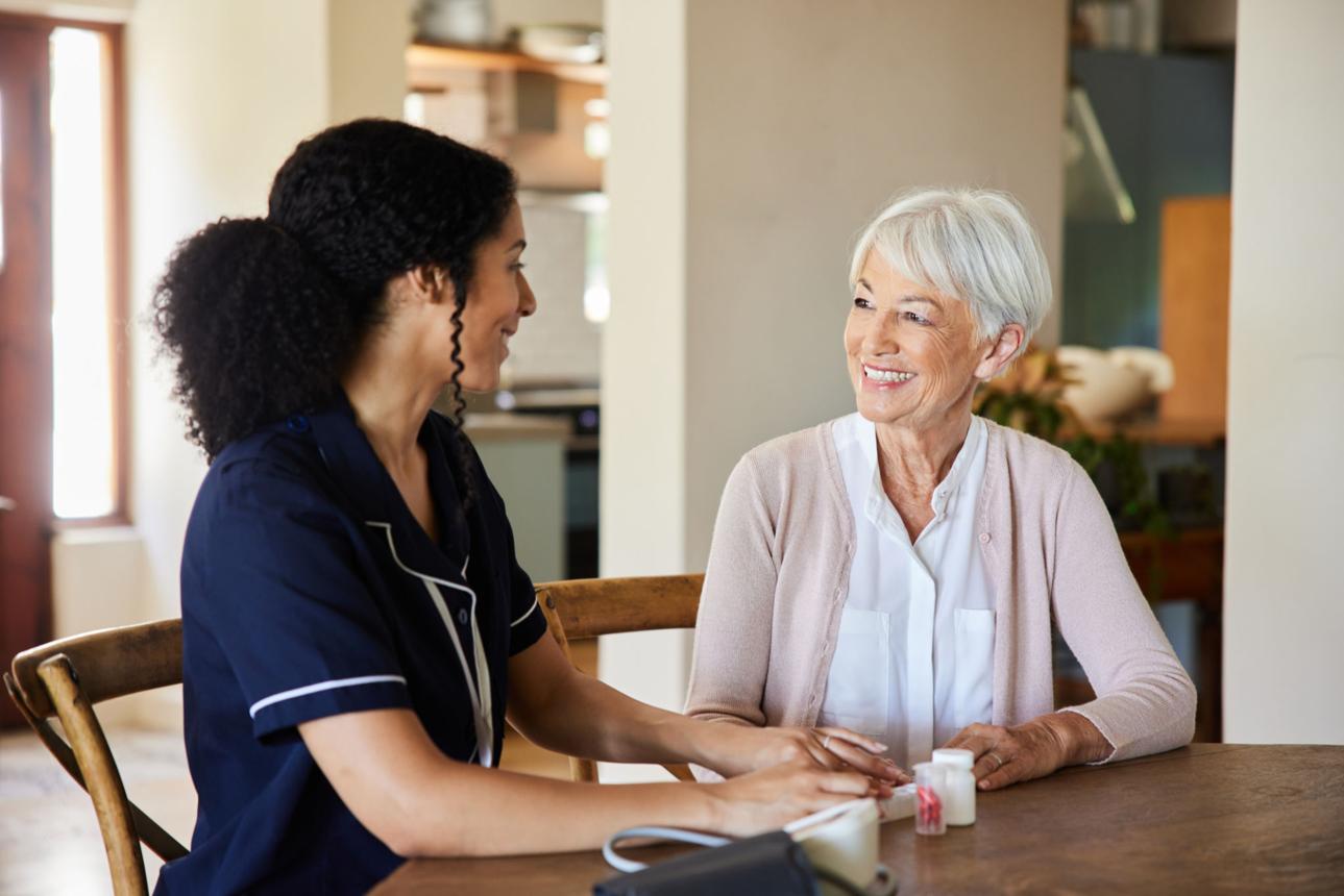 Caregiver and elderly client sharing a warm conversation at home